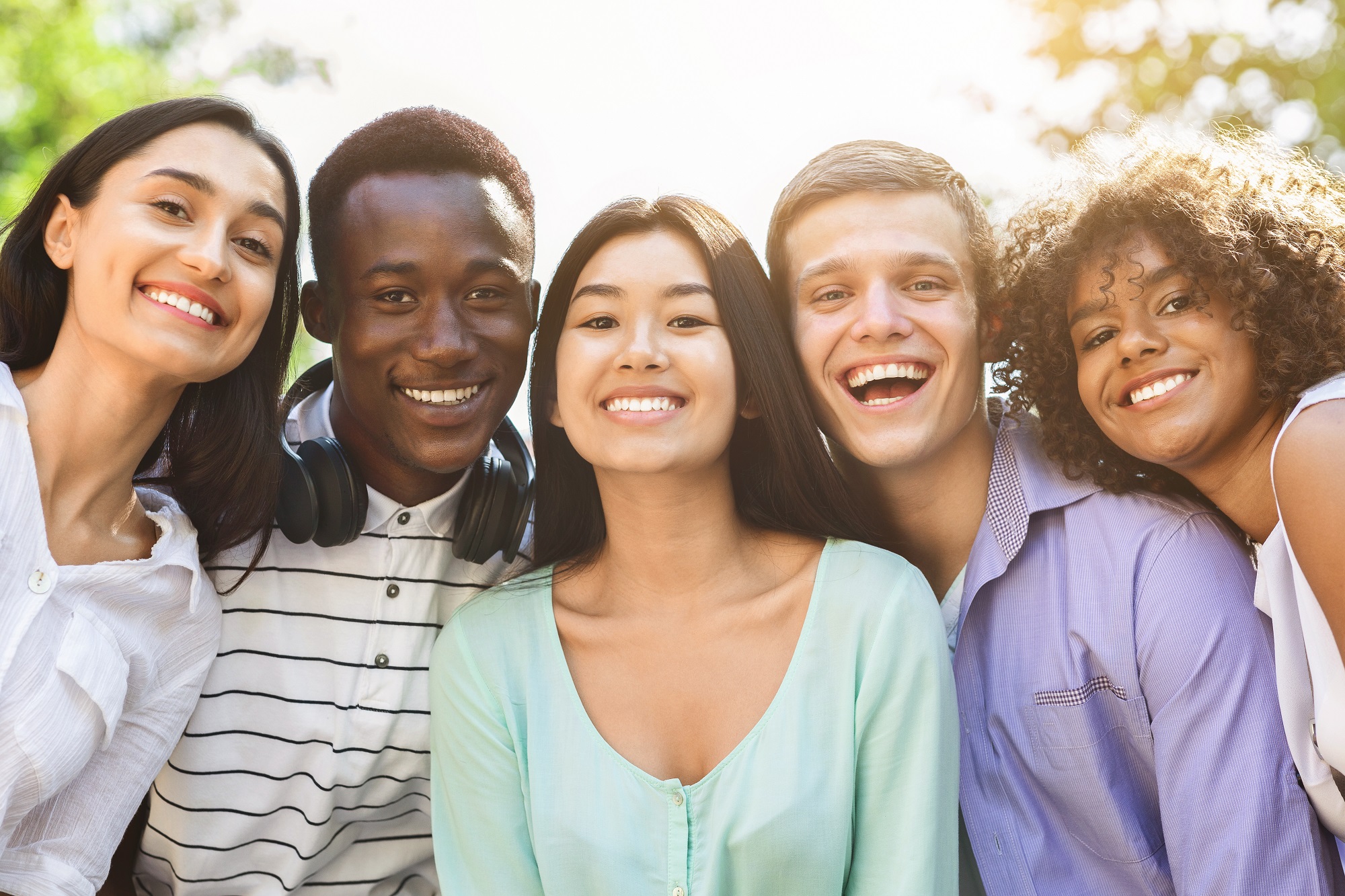 A group of young people putting their heads together and smiling at the camera